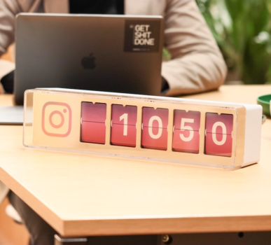 A man sitting at a desk with a laptop and instagram clock.