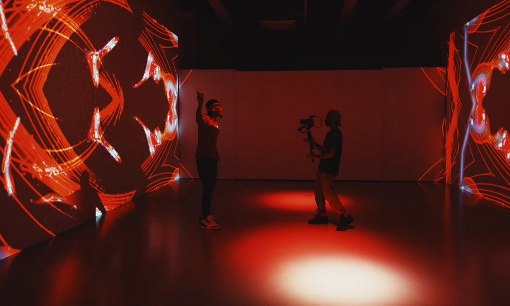 Two people standing in a dark room.