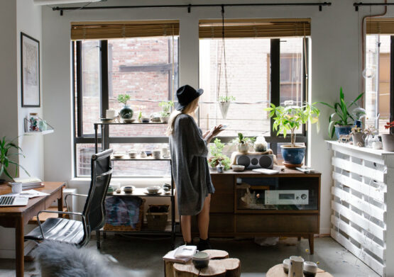 A woman is sitting in a room with a desk and plants.